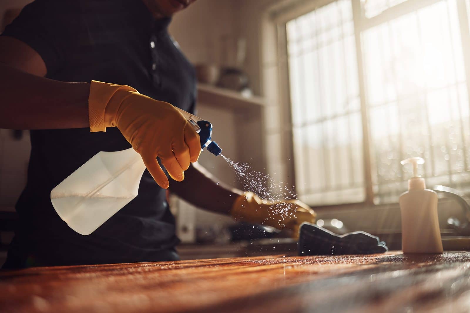 Homem higieniza a bancada de uma cozinha residencial nos Estados Unidos
