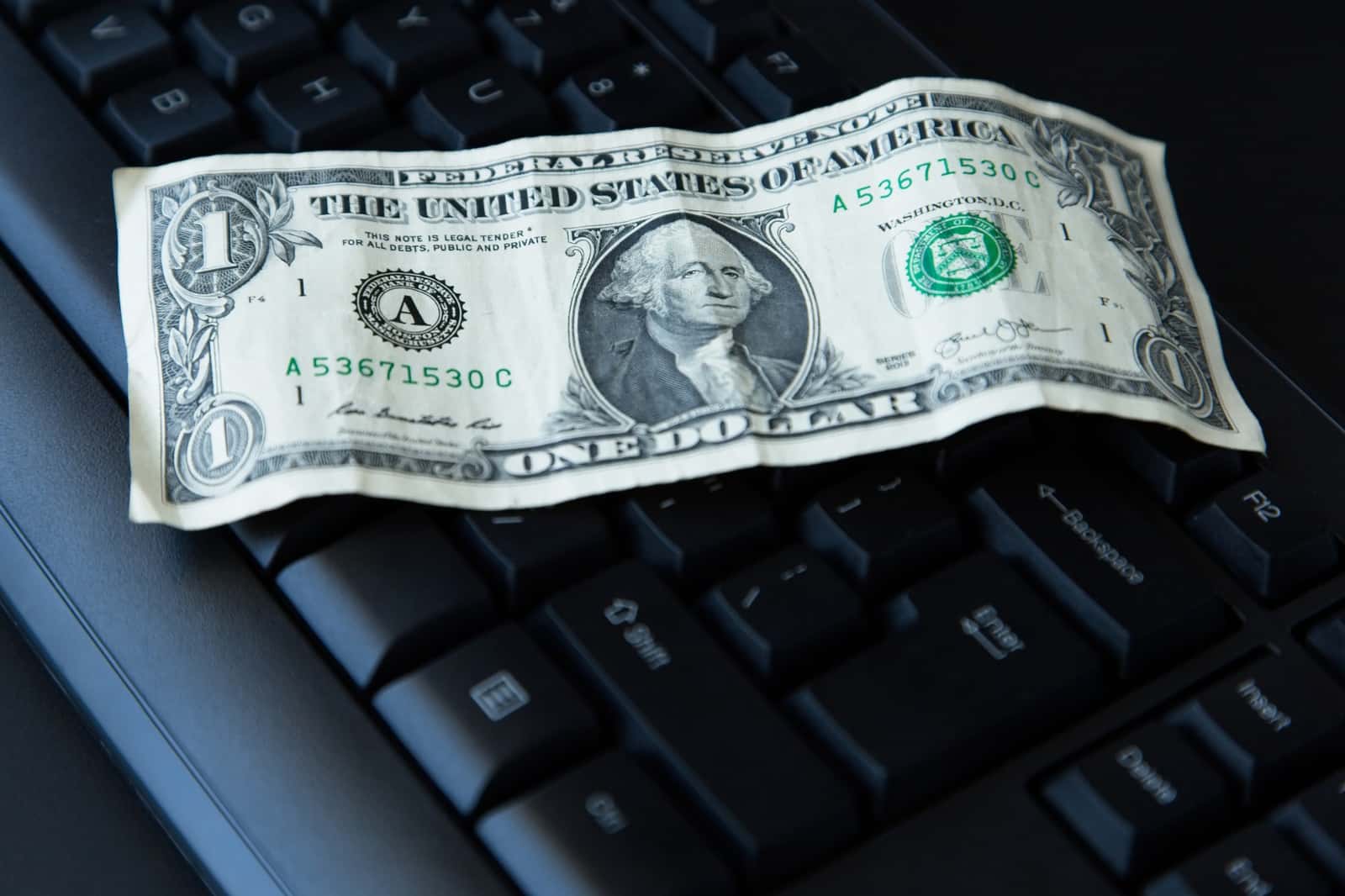 Nota de um dólar americano sobre um teclado de computador